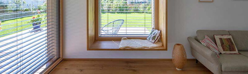 Helle Wohnlandschaft mit Fensterbank, Blick auf den Garten und einem gemütlichen Sofa, das zum Entspannen einlädt. | © Name