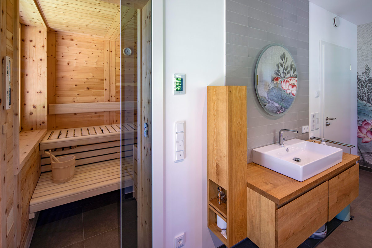 Ein modernes Badezimmer in einem Holzhaus in Glonn präsentiert eine stilvolle Sauna mit Holzdekor.