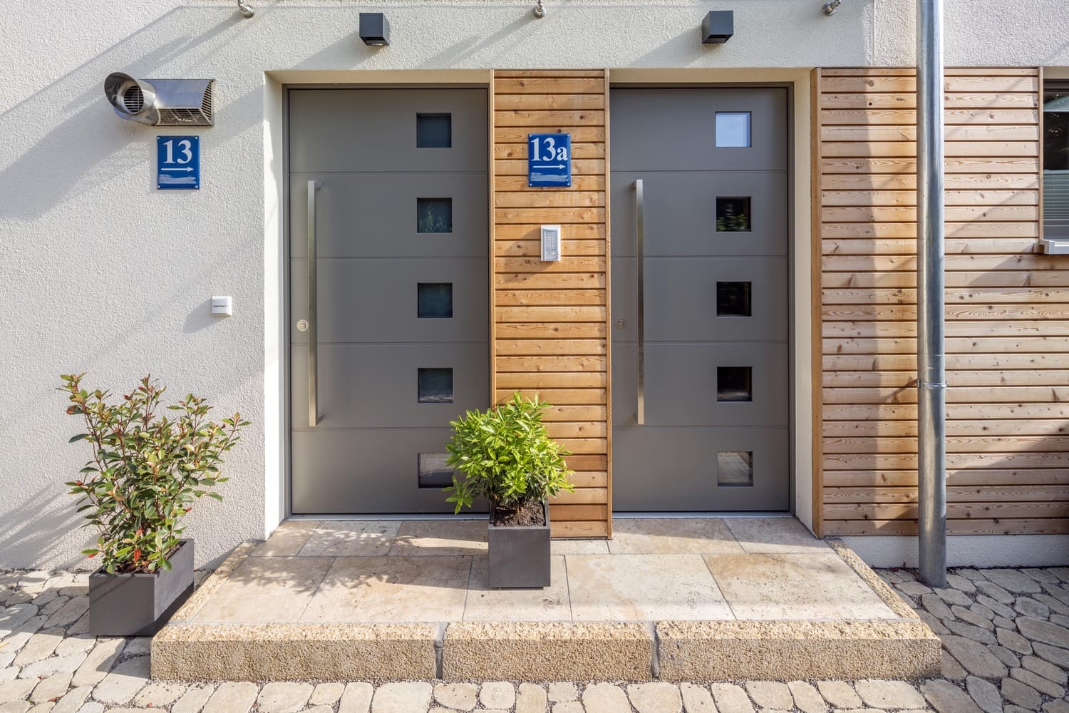 Mehrfamiliehaus, verputztes Holzhaus in München, Haustüren