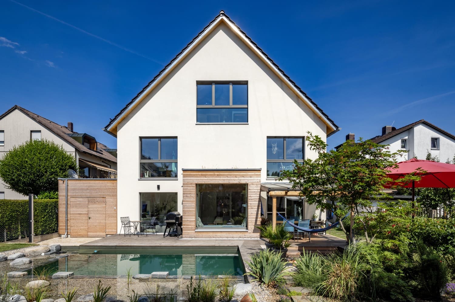 Mehrfamiliehaus, verputztes Holzhaus in München, Schwimmteich,