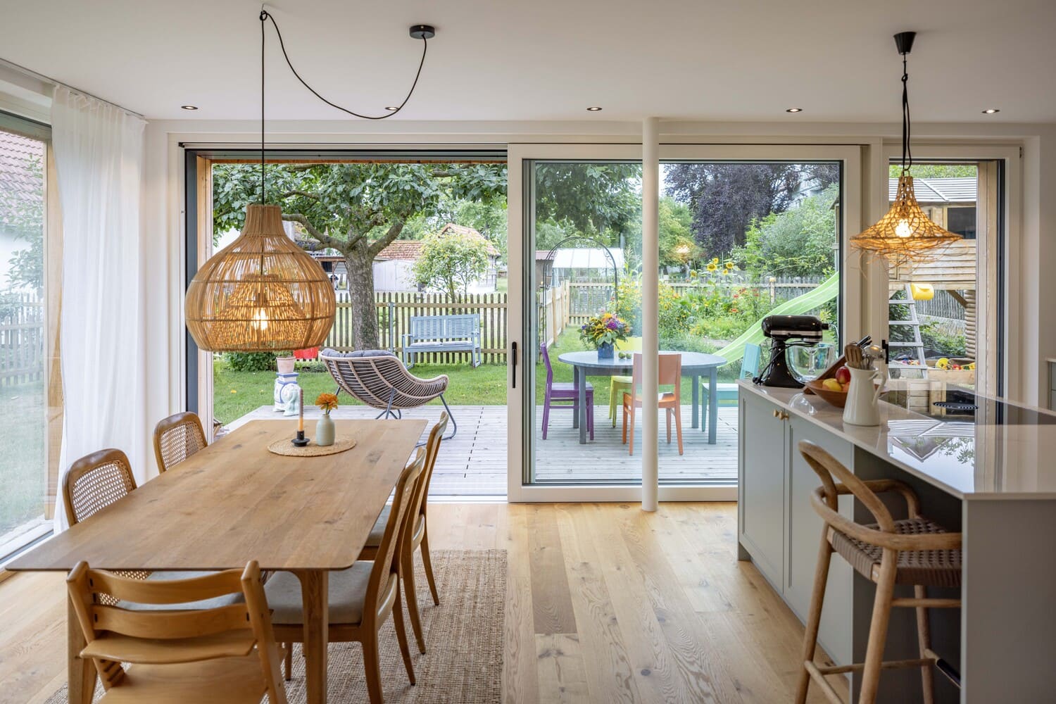 Essbereich und Küche mit Holzboden und Küchenblock, große Hebeschiebetür